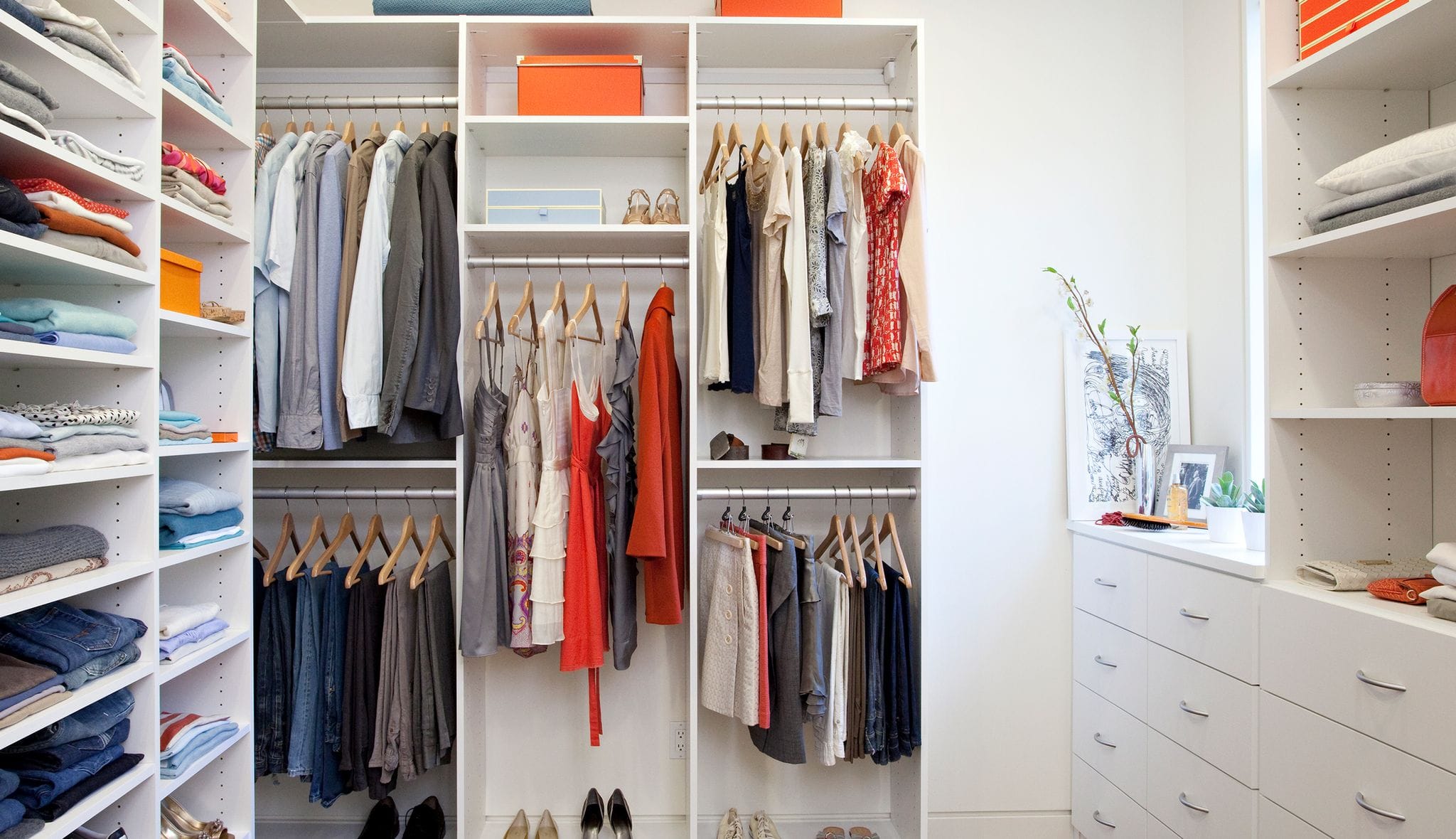 Remodeled walk in closet shown with custom dresser drawers in white finish by California Closets