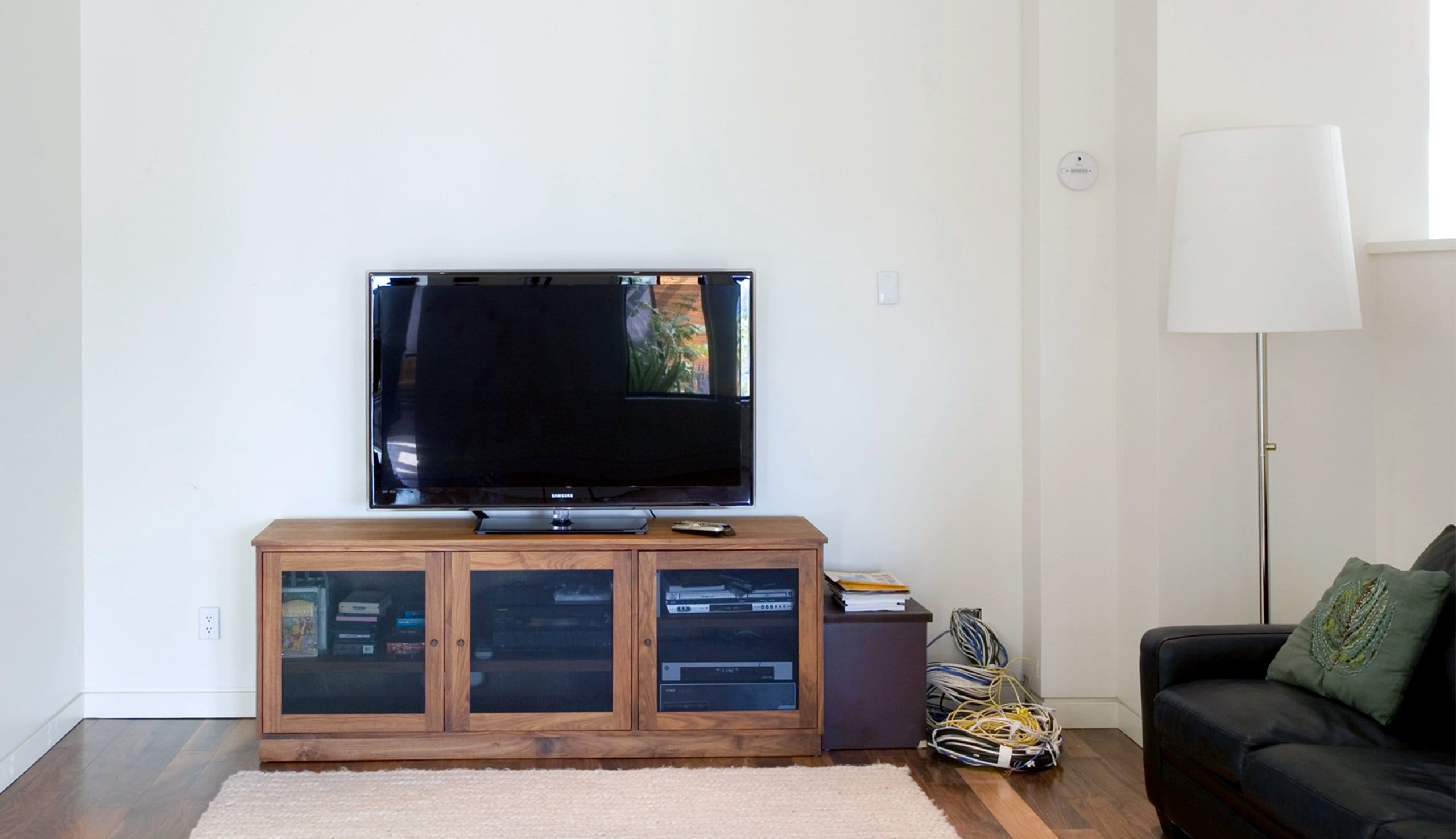 Before renovation of an outdated entertainment center living rom space with little storage California Closets